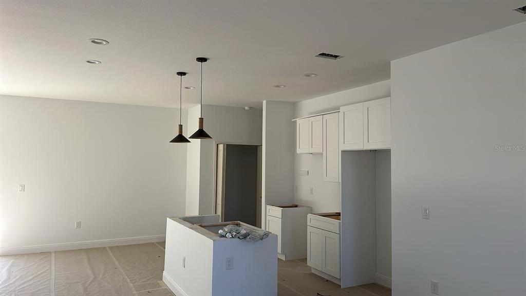 An unfinished kitchen features white cabinets, a center island, and two pendant lights — 12167 FLORENCE AVENUE, PORT CHARLOTTE, FL