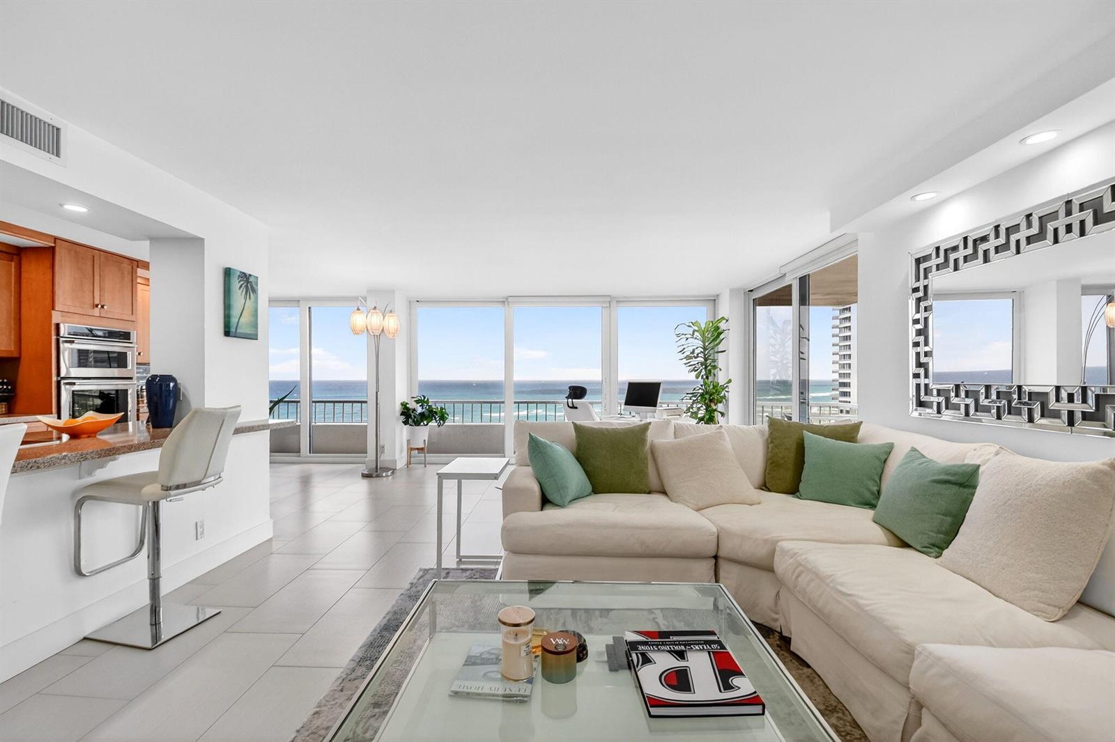 A bright living room with a white sectional sofa, glass coffee table, and ocean views — 5540 N Ocean Drive # 9b, Singer Island FL 33404, SINGER ISLAND, FL