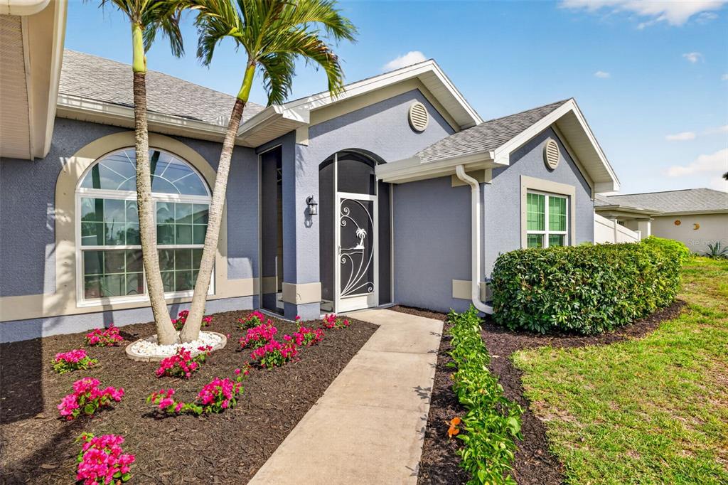 A blue house exterior features a front walkway, palm trees, and a decorative screen door — 1417 NW 16TH PLACE, CAPE CORAL, FL
