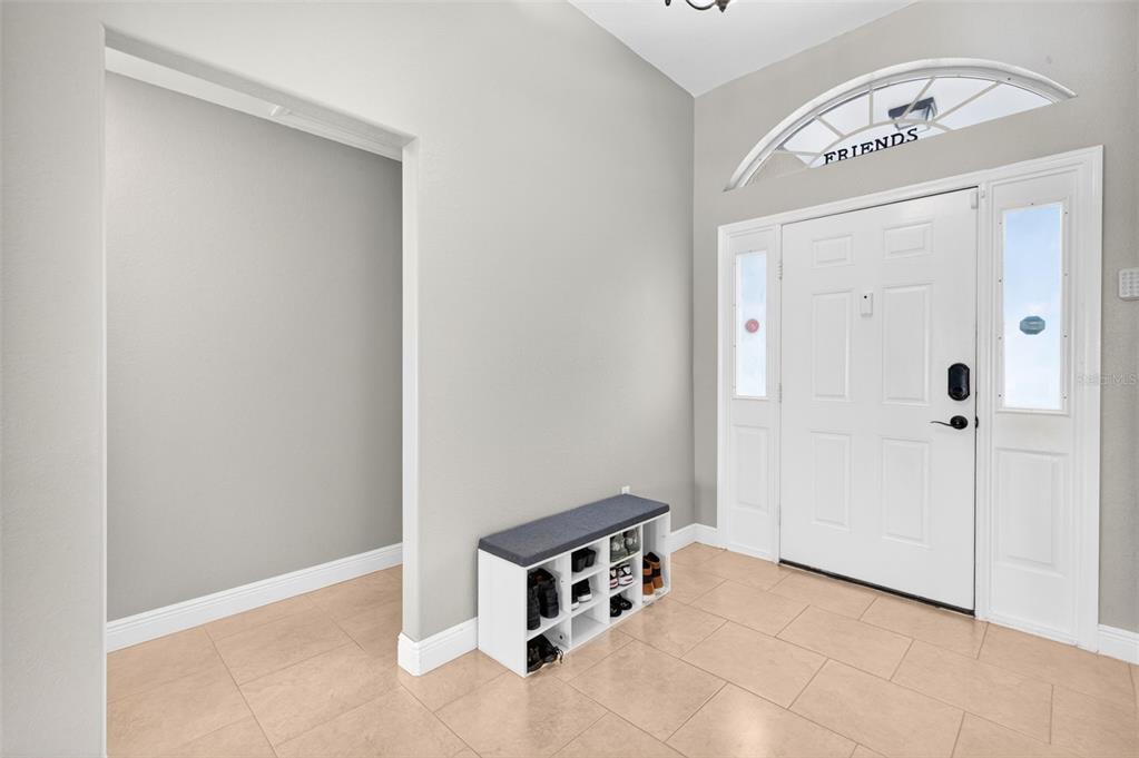 An entryway features light-colored tile flooring, a white front door, and a shoe storage bench — 1417 NW 16TH PLACE, CAPE CORAL, FL