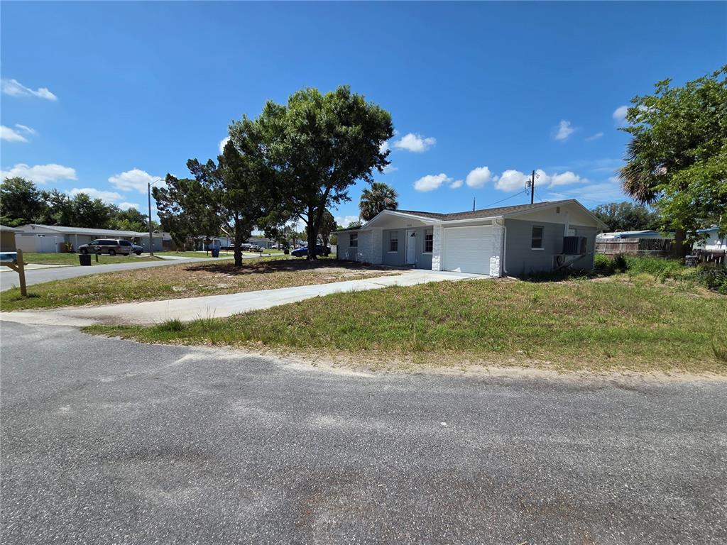 A single-story gray house with a garage sits on a grassy lot with trees — 4616 IRENE LOOP, NEW PORT RICHEY, FL