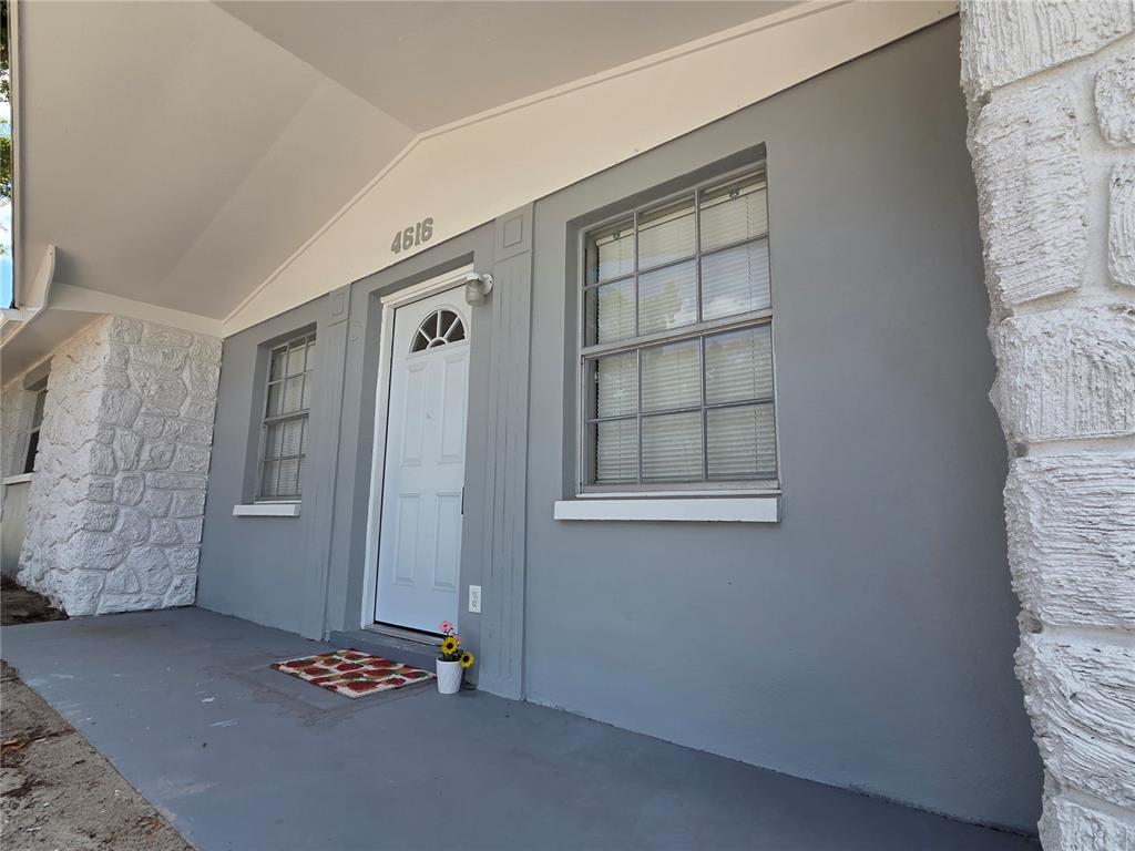 A gray exterior wall features a white front door, two windows, and stone siding — 4616 IRENE LOOP, NEW PORT RICHEY, FL