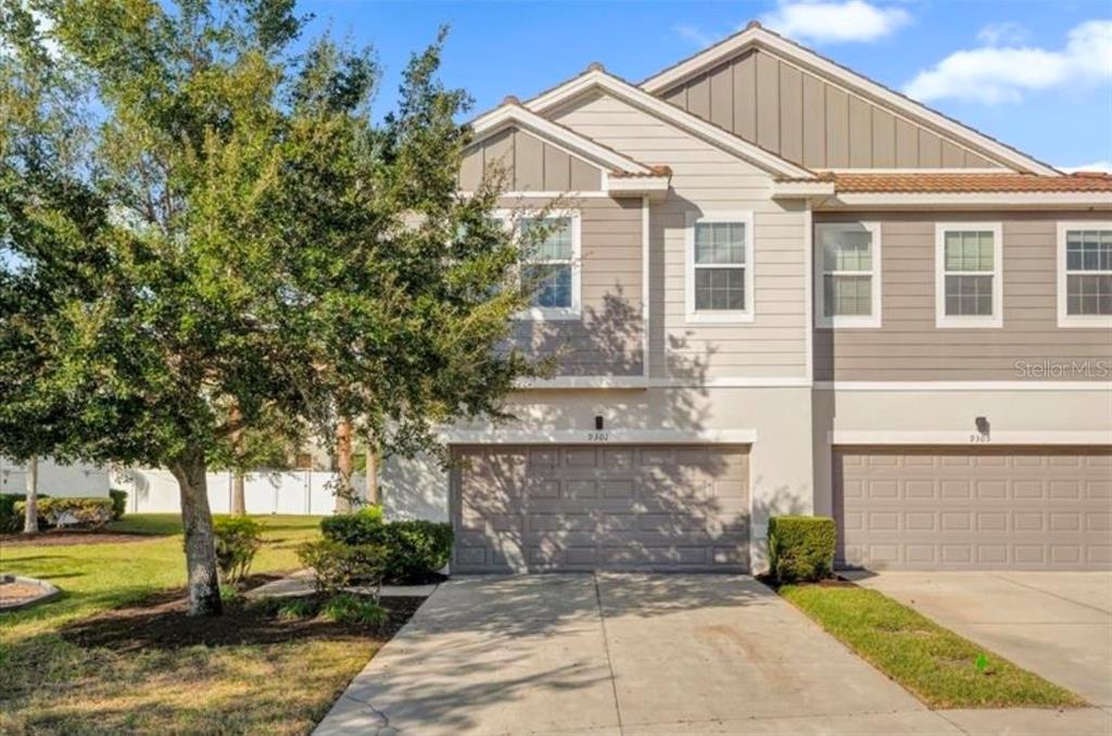 A two-story house exterior with gray siding, a brown front door, and palm trees — 9301 WATCHET WAY, ORLANDO, FL