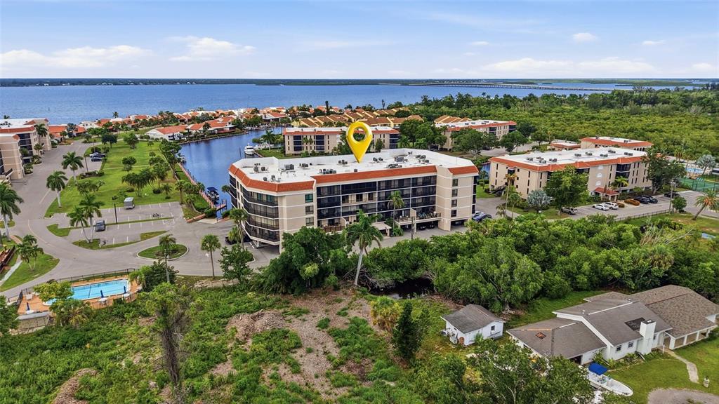 An aerial view shows a multi-story apartment building with a red roof near water — 25188 MARION AVE UNIT D307, PUNTA GORDA, FL
