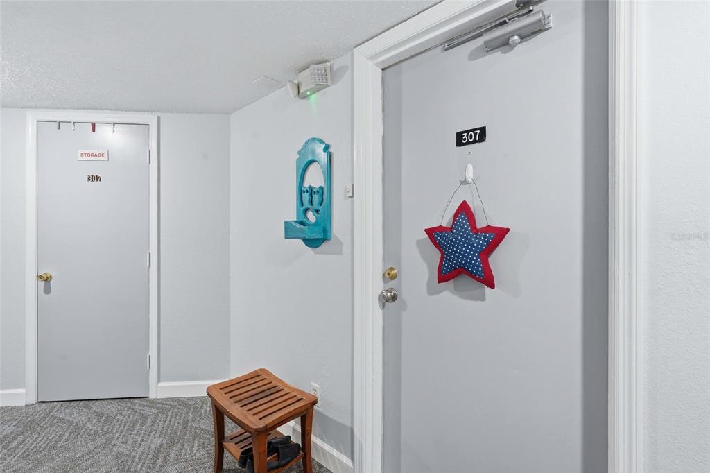 A hallway features two gray doors labeled 307, a wooden bench, and a star decoration — 25188 MARION AVE UNIT D307, PUNTA GORDA, FL
