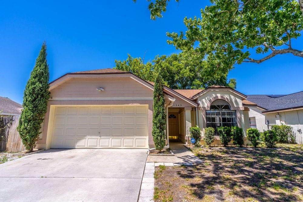 A single-story house with a beige stucco exterior, a two-car garage, and a front walkway — 1345 TINDARO DRIVE, APOPKA, FL