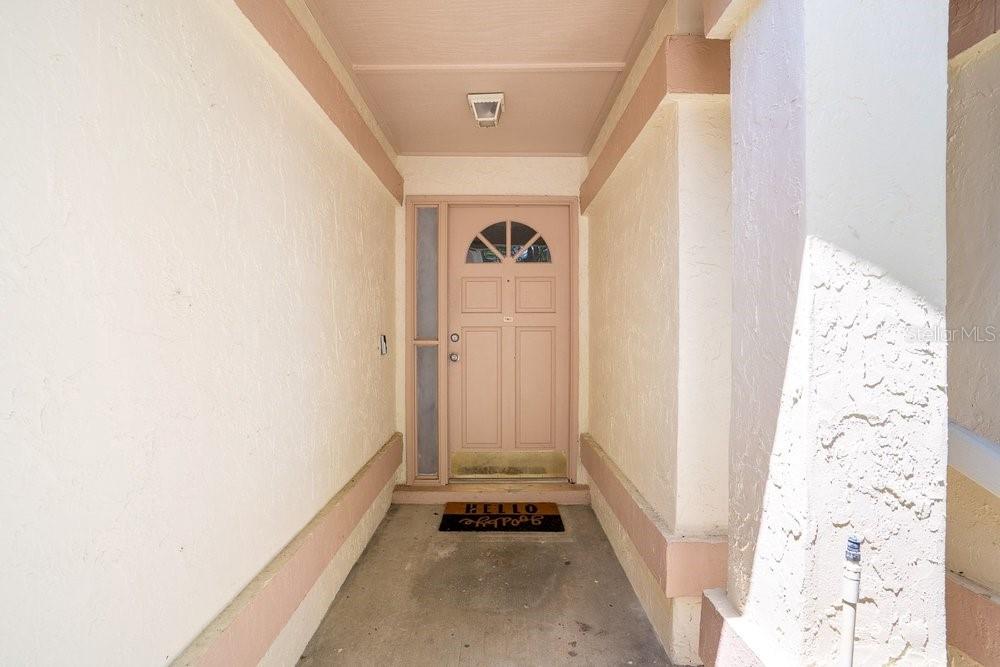 A covered entryway features a light-colored front door with a decorative window and a doormat — 1345 TINDARO DRIVE, APOPKA, FL