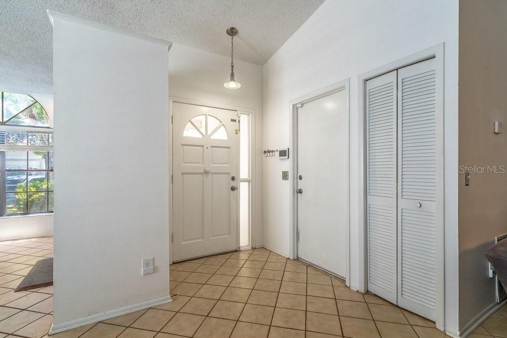 An entryway features a white front door, tiled floors, a closet, and a pendant light — 1345 TINDARO DRIVE, APOPKA, FL