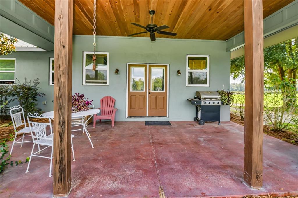 A covered patio features a concrete floor, wooden ceiling, ceiling fan, and outdoor furniture — 6155 NW 145TH AVE ROAD, MORRISTON, FL