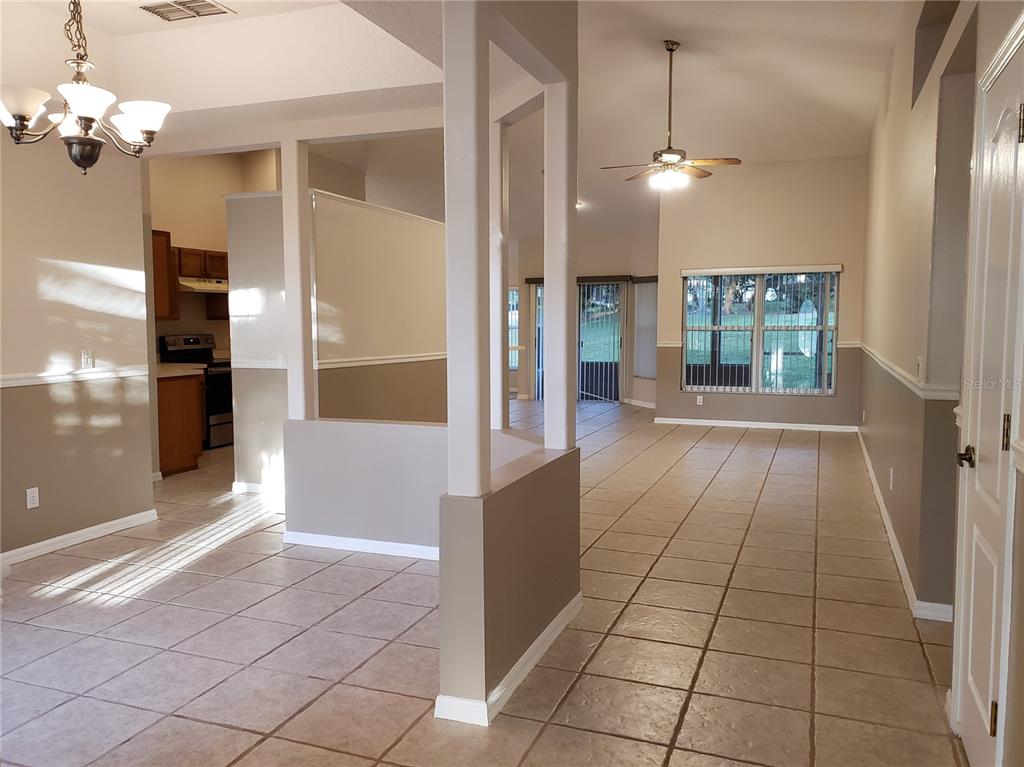 An open-concept living area features tile flooring, neutral walls, and a view into the kitchen — 1612 SWEETWATER WEST CIRCLE, APOPKA, FL