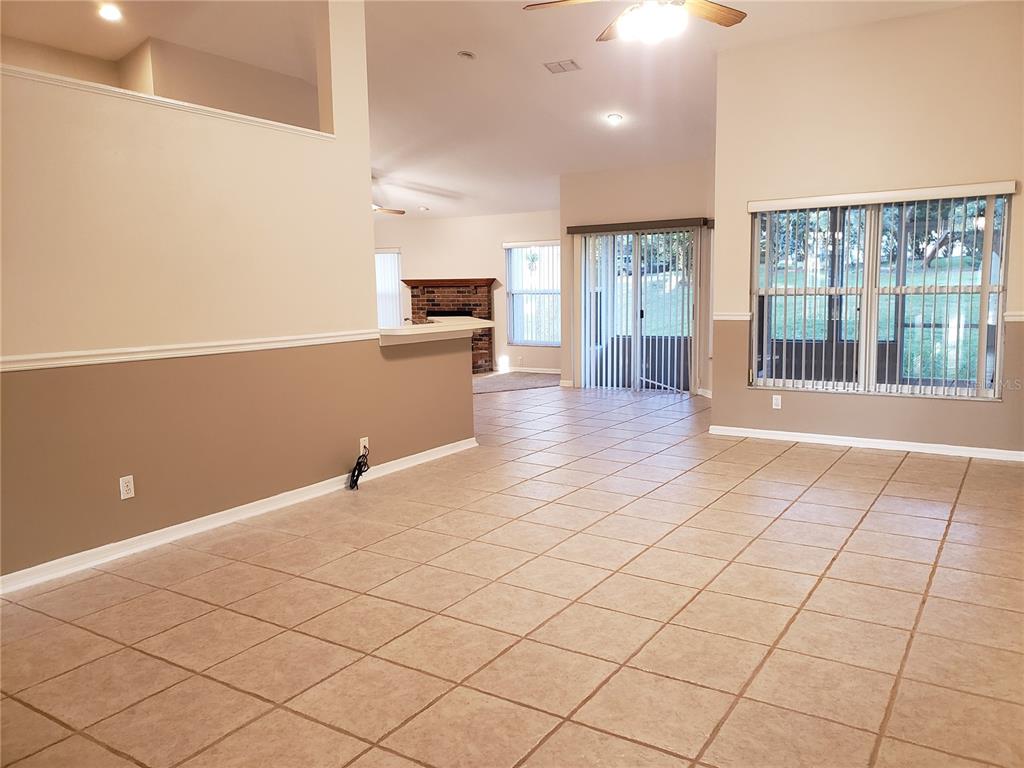 An open-concept living area features beige walls, tile flooring, a fireplace, and sliding glass doors — 1612 SWEETWATER WEST CIRCLE, APOPKA, FL