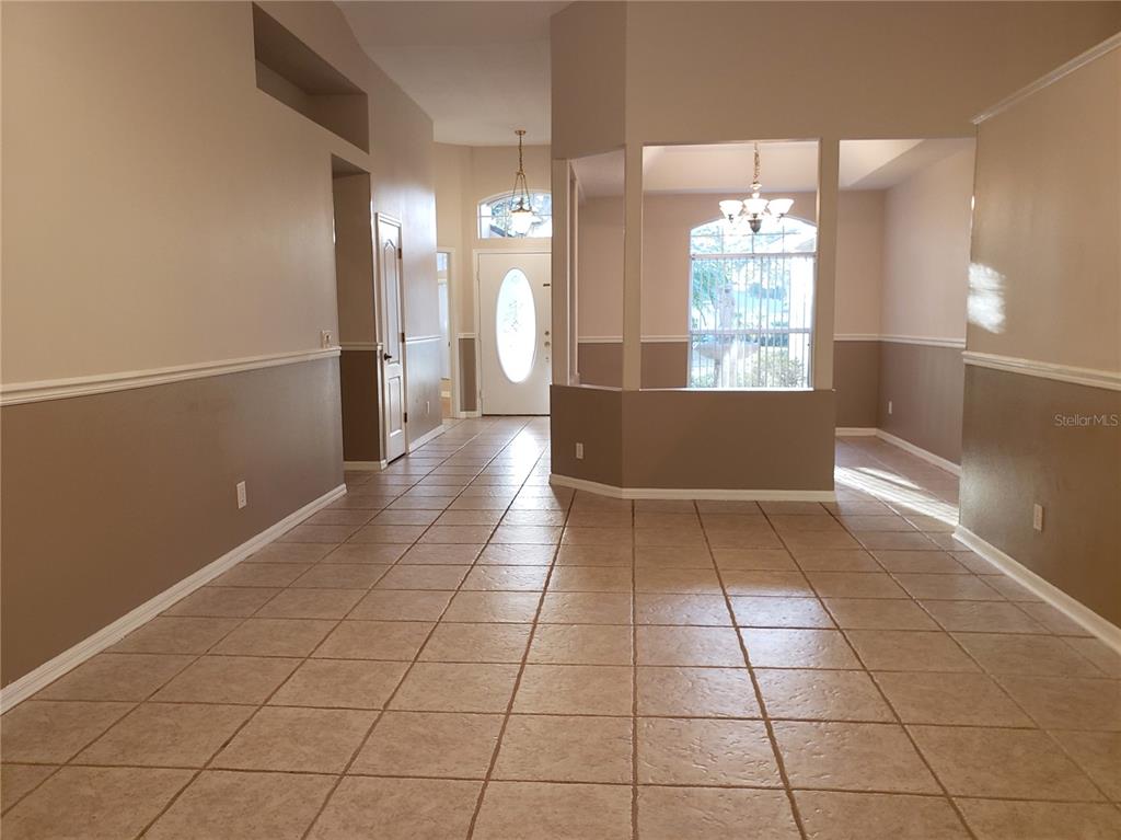 An entryway with tile flooring leads to a front door and an adjacent dining area — 1612 SWEETWATER WEST CIRCLE, APOPKA, FL
