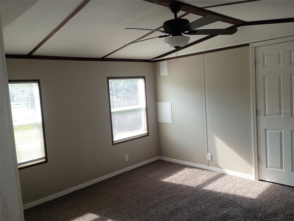 A bedroom with beige walls, brown carpet, a ceiling fan, and two windows — 11441 KO DRIVE, LAKELAND, FL
