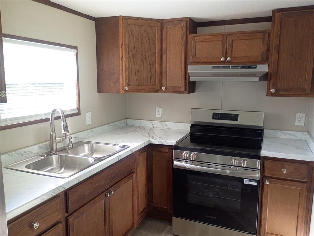A kitchen with wood cabinets, marble-look laminate countertops, and stainless steel appliances — 11441 KO DRIVE, LAKELAND, FL