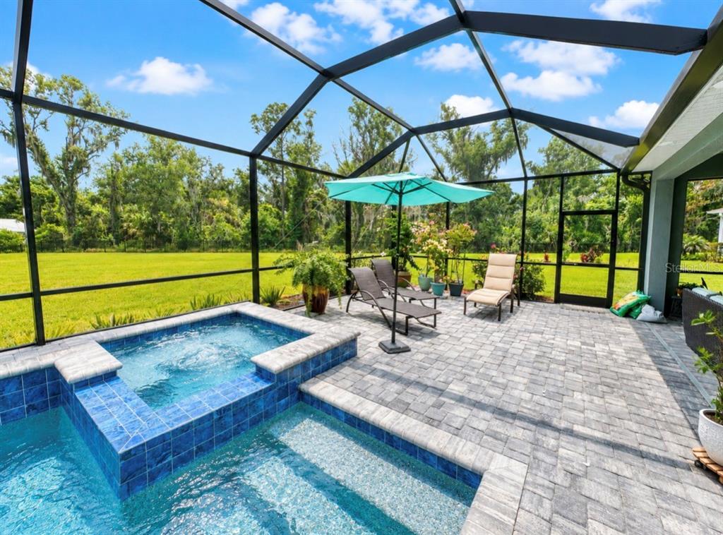 A screened-in patio features a tiled spa, a small pool, and lounge chairs on pavers — 5322 124TH AVENUE E, PARRISH, FL