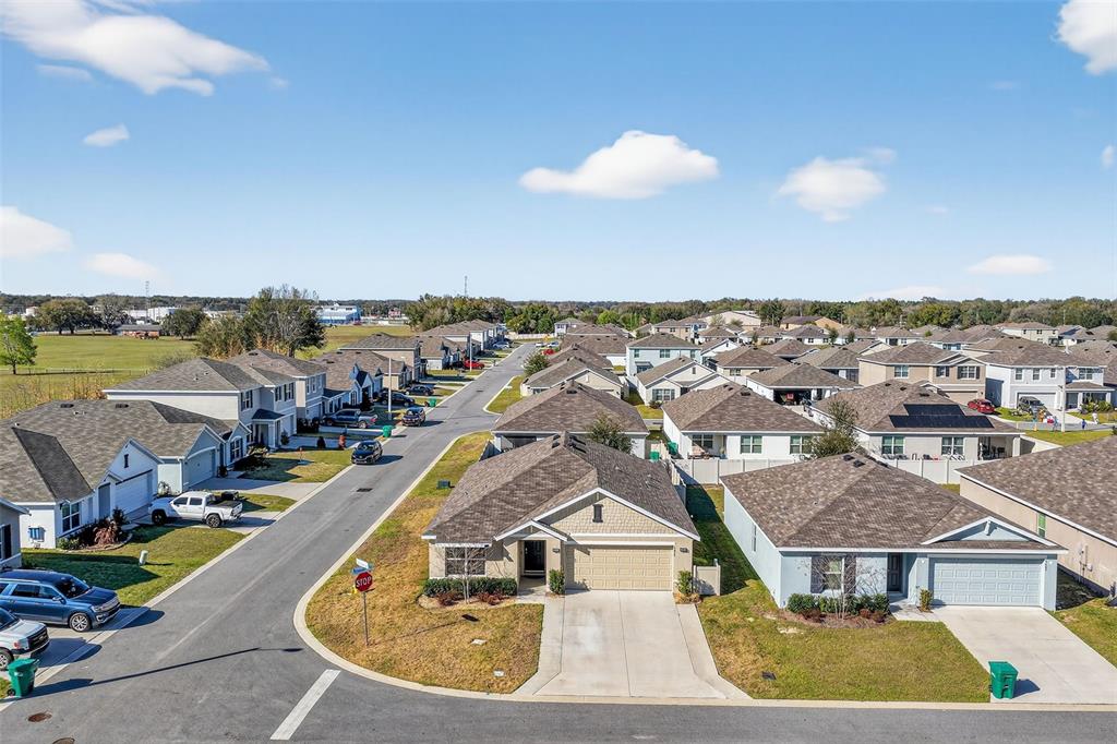 An aerial view shows a suburban neighborhood with single-family homes and paved streets — 4656 CROSSROADS LANE, WILDWOOD, FL
