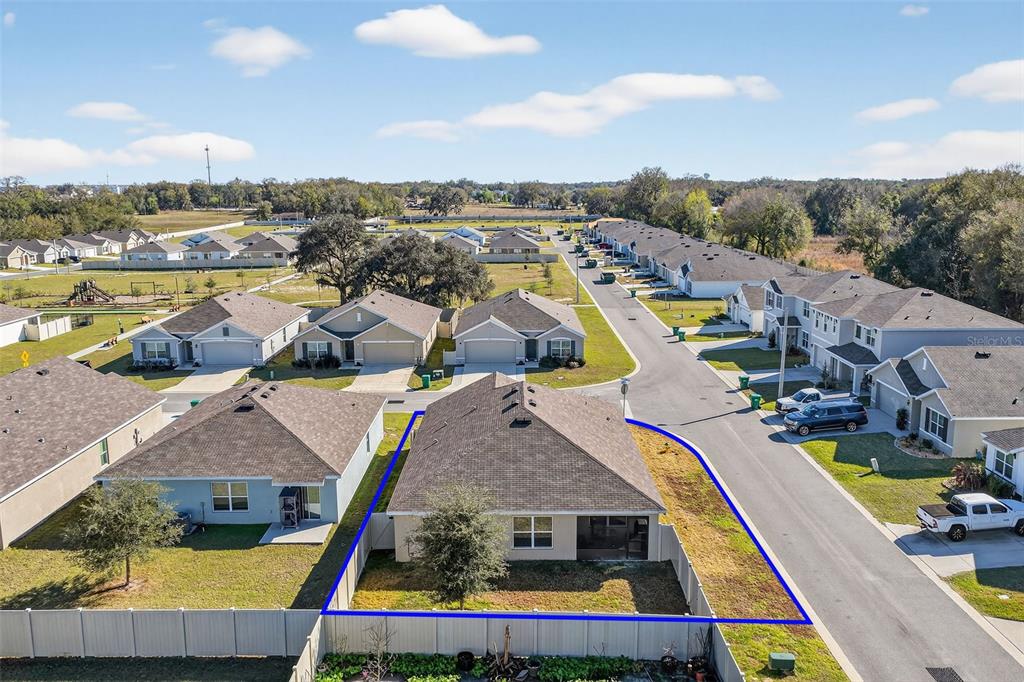 An aerial view shows a single-story house with a fenced backyard in a suburban neighborhood — 4656 CROSSROADS LANE, WILDWOOD, FL
