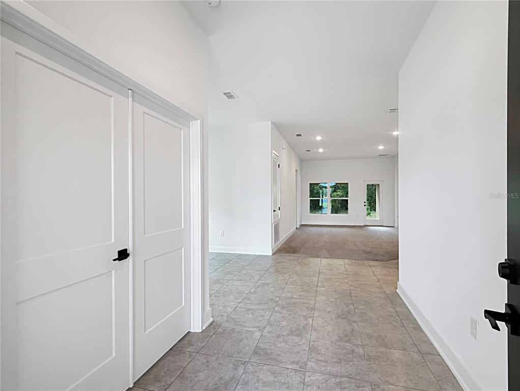 A tiled entryway leads into a carpeted living area with white walls and large windows — 7648 BENT TREE LOOP, ST CLOUD, FL