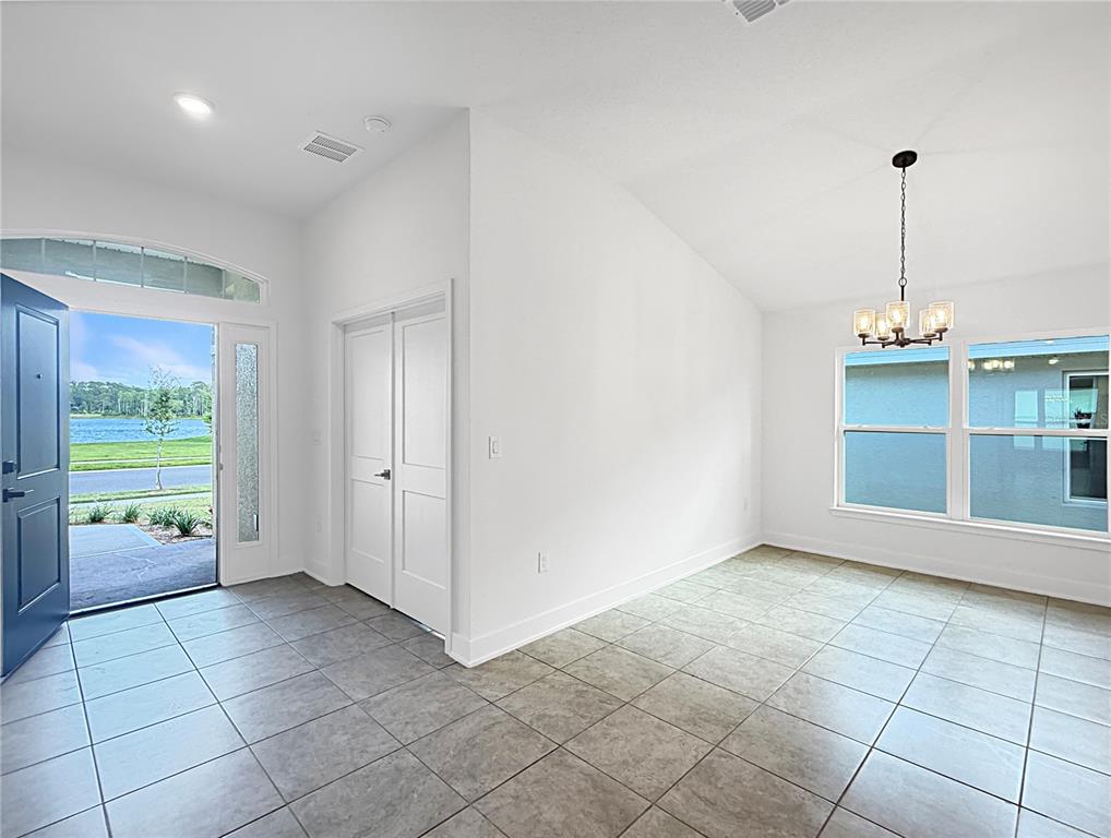 A bright entryway and dining area feature white walls, tile flooring, and a chandelier — 7648 BENT TREE LOOP, ST CLOUD, FL