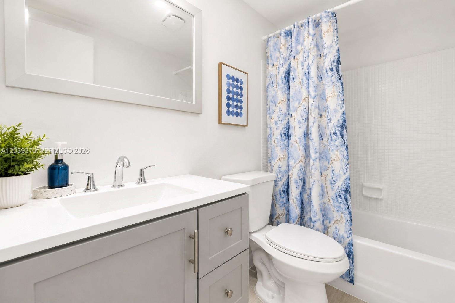 A bathroom features a gray vanity, white countertop, toilet, and a blue patterned shower curtain — 7605 NW 5th Pl # 103, Margate FL 33063, MARGATE, FL