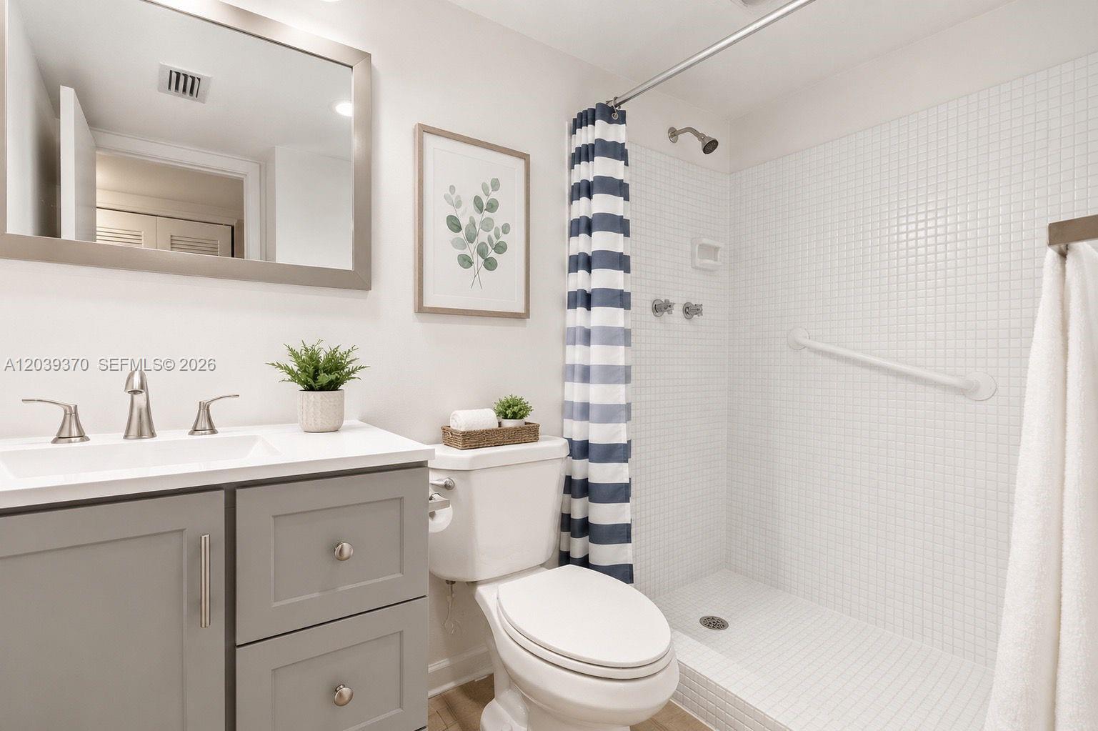 A bathroom features a gray vanity, a white toilet, and a tiled walk-in shower — 7605 NW 5th Pl # 103, Margate FL 33063, MARGATE, FL