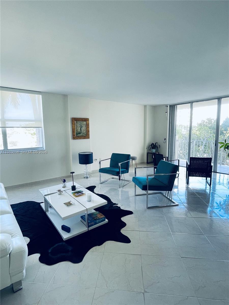 A bright living room features white tile floors, a white coffee table, and teal chairs — 11111 Biscayne Blvd # 4E, Miami FL 33181, MIAMI, FL