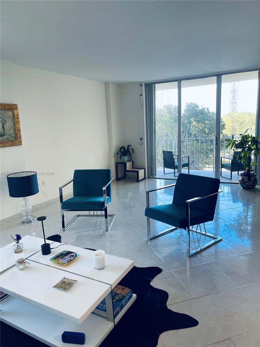 A living room features two teal armchairs, a white coffee table, and a balcony view — 11111 Biscayne Blvd # 4E, Miami FL 33181, MIAMI, FL