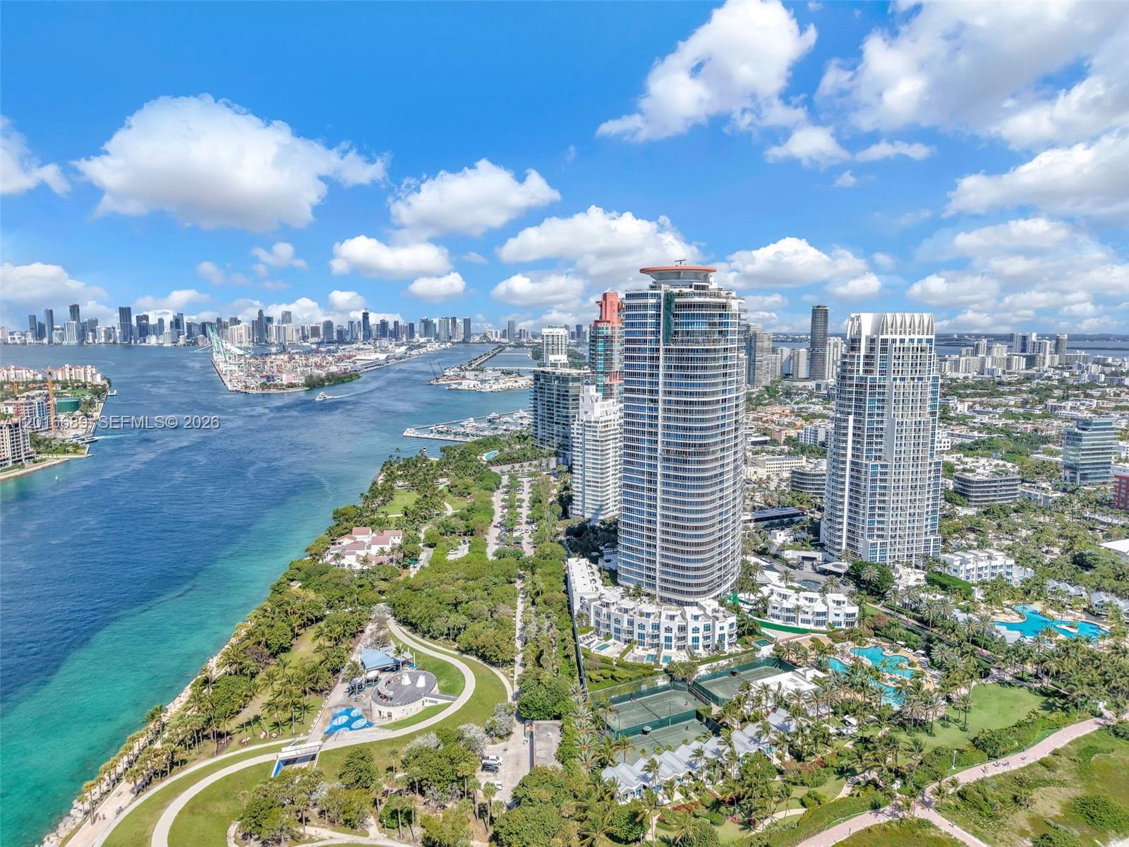 An aerial view shows high-rise residential towers, a park, tennis courts, and a waterfront — 100 S Pointe Dr # 801, Miami Beach FL 33139, MIAMI BEACH, FL