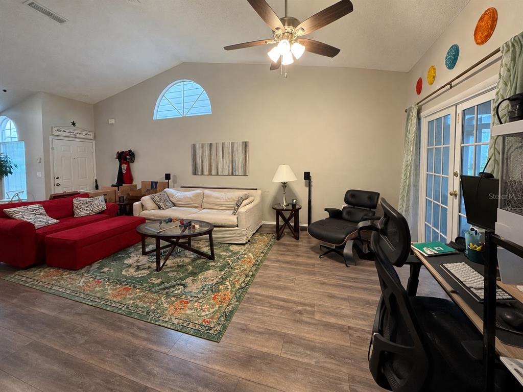 A living room features a red sofa, a white sofa, a rug, and a desk area — 2390 GUN FLINT TRAIL, PALM HARBOR, FL