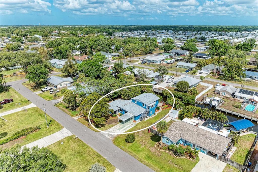 An aerial view shows a blue two-story house with a metal carport and surrounding trees — 4518 7TH STREET COURT E, ELLENTON, FL