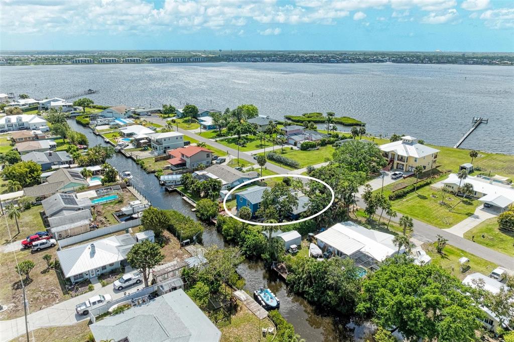 An aerial view shows a blue house surrounded by trees next to a canal — 4518 7TH STREET COURT E, ELLENTON, FL