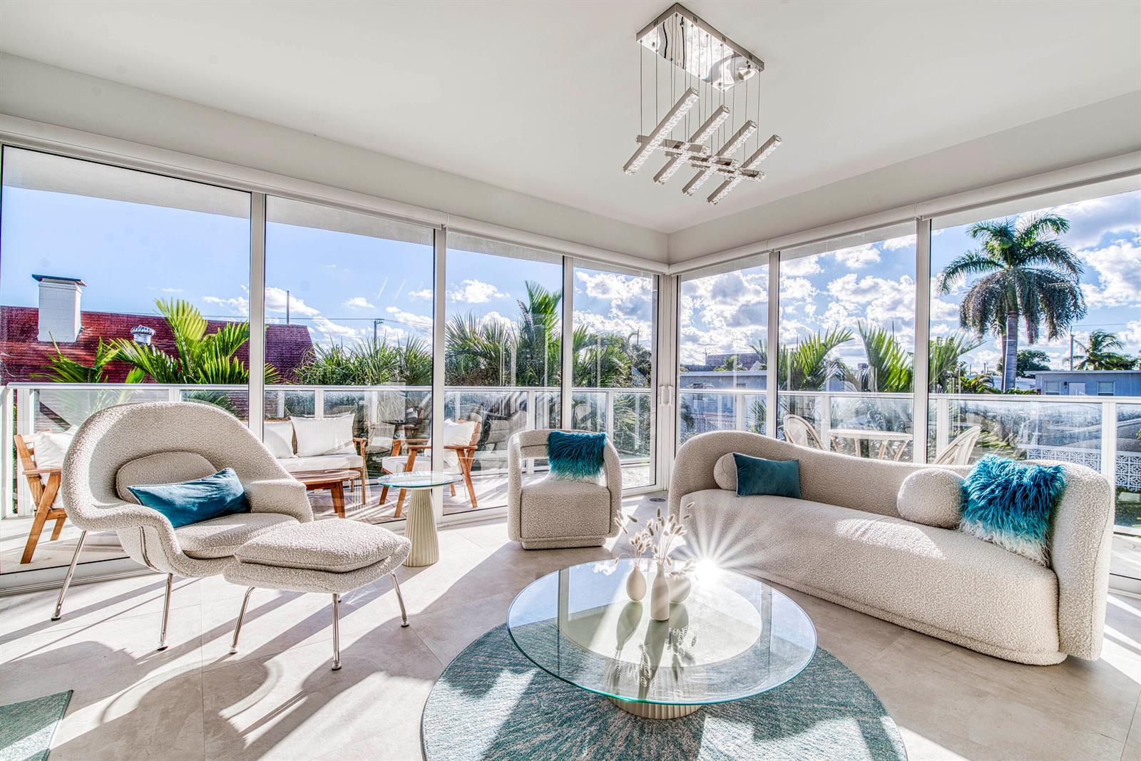 A sunroom features modern furniture, a glass coffee table, and floor-to-ceiling windows overlooking a balcony — 117 Lake Avenue # 204, FL 33460, FL
