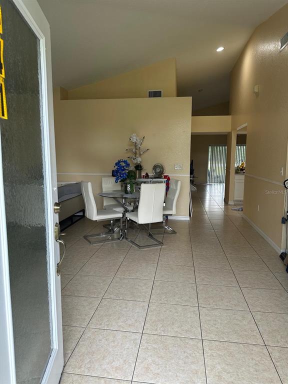 A dining area with a glass table and white chairs sits on a tiled floor — 441 CARDINAL COURT, POINCIANA, FL