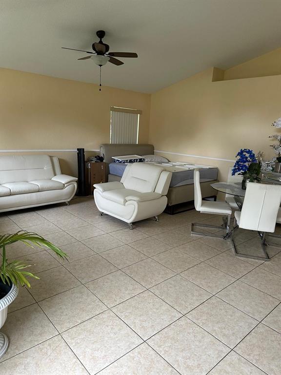 A room with light-colored tile floors, a white sofa, an armchair, and a bed — 441 CARDINAL COURT, POINCIANA, FL