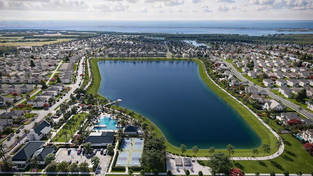 Aerial view of a residential community featuring a large lake, swimming pool, and tennis courts — 7804 LAKE FLORES AVENUE, BRADENTON, FL