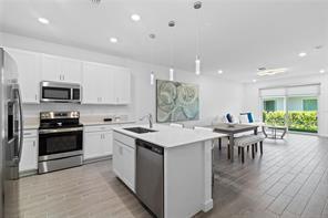 A modern kitchen with white cabinets, stainless steel appliances, and an island with a sink — 14534 Highland Center Way, Delray Beach FL 33446, DELRAY BEACH, FL