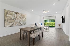 A dining area with a wooden table and benches sits before a living room space — 14534 Highland Center Way, Delray Beach FL 33446, DELRAY BEACH, FL