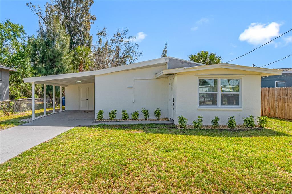 A single-story house with a white stucco exterior, a carport, and a front lawn — 6908 11TH AVENUE E, PALMETTO, FL