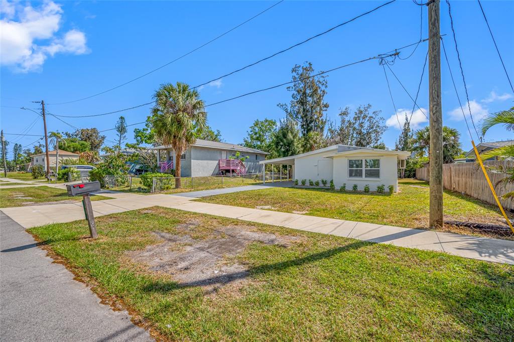 A single-story house with a carport sits behind a sidewalk and a grassy front yard — 6908 11TH AVENUE E, PALMETTO, FL