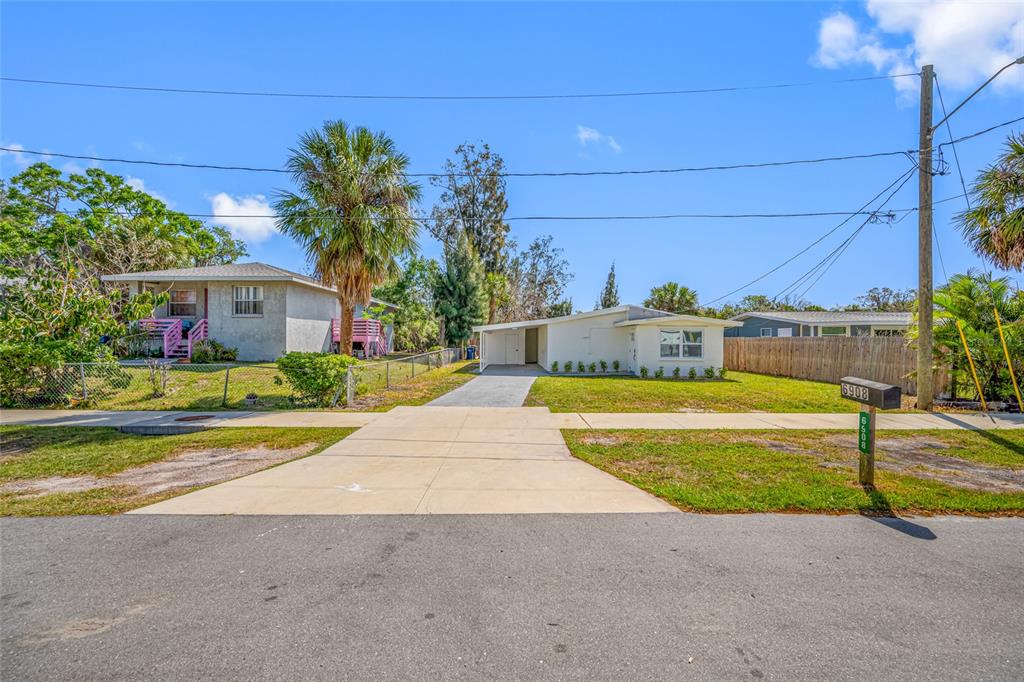 A single-story house with a carport and a front yard sits behind a concrete driveway — 6908 11TH AVENUE E, PALMETTO, FL