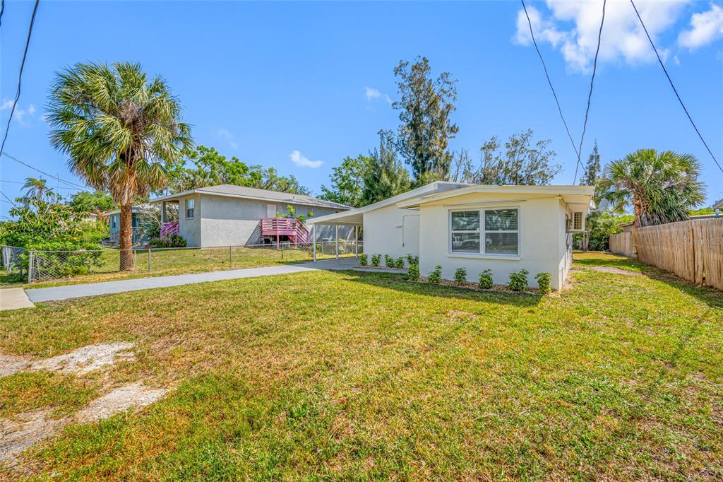 A light-colored single-story house with a carport and a large front lawn — 6908 11TH AVENUE E, PALMETTO, FL