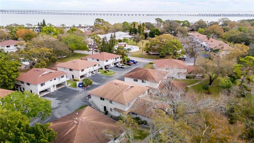An aerial view shows multiple multi-story residential buildings surrounded by trees near a large body — 1832 BOUGH AVENUE UNIT 3, CLEARWATER, FL