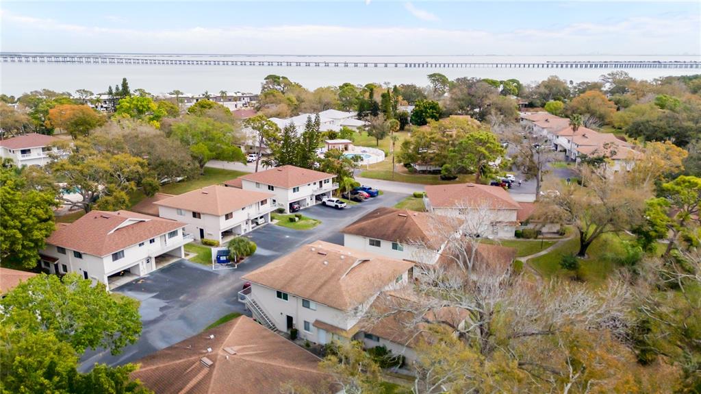 An aerial view shows multiple multi-story residential buildings with brown roofs near a large body of water — 1832 BOUGH AVENUE UNIT 3, CLEARWATER, FL