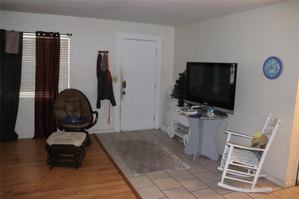 A living room features a white front door, tile and wood flooring, and a television — 16 S HARRISON STREET, BEVERLY HILLS, FL