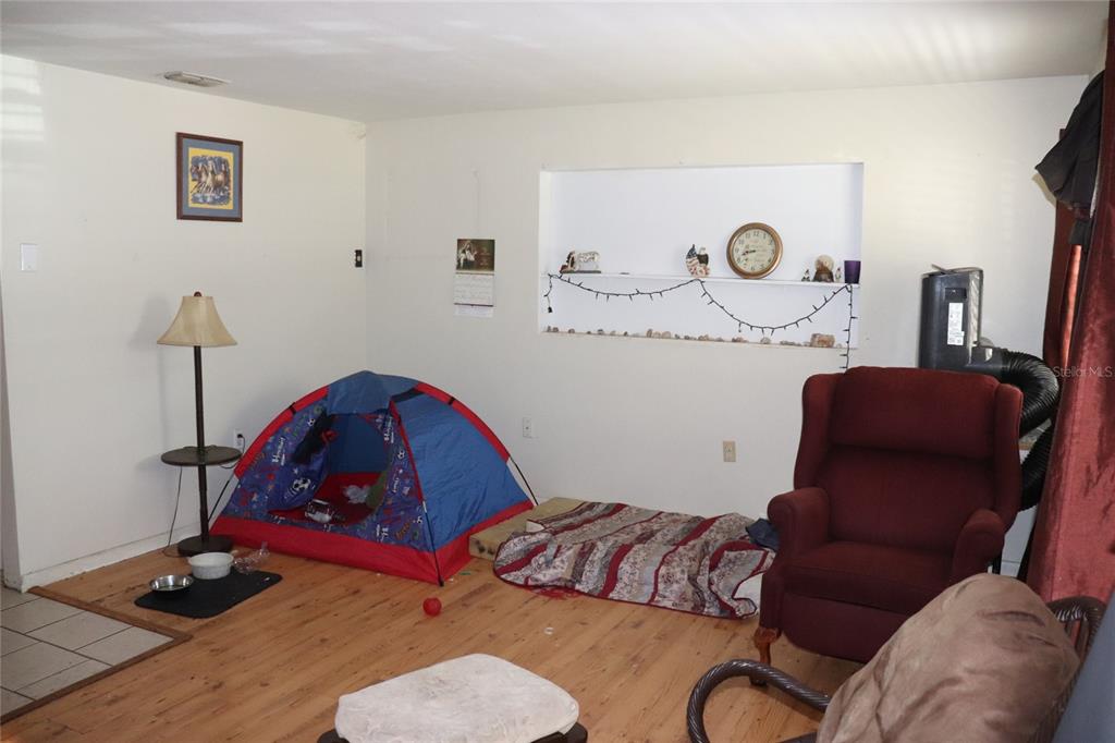 A living room with wood flooring, a small play tent, and a recessed wall shelf — 16 S HARRISON STREET, BEVERLY HILLS, FL