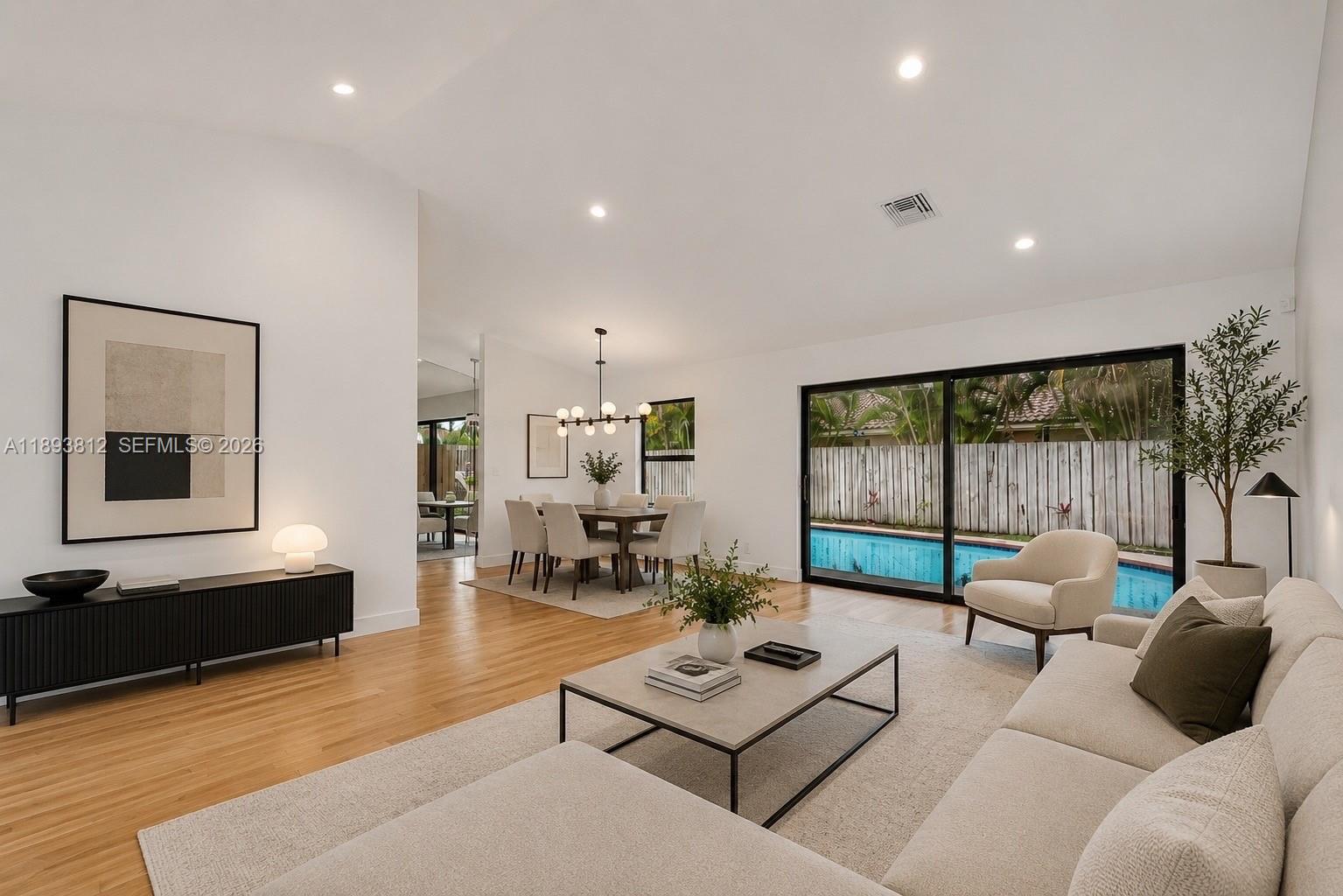 A bright living and dining area features hardwood floors, white walls, and a backyard pool — 1855 NW 106th Ter, Plantation FL 33322, PLANTATION, FL