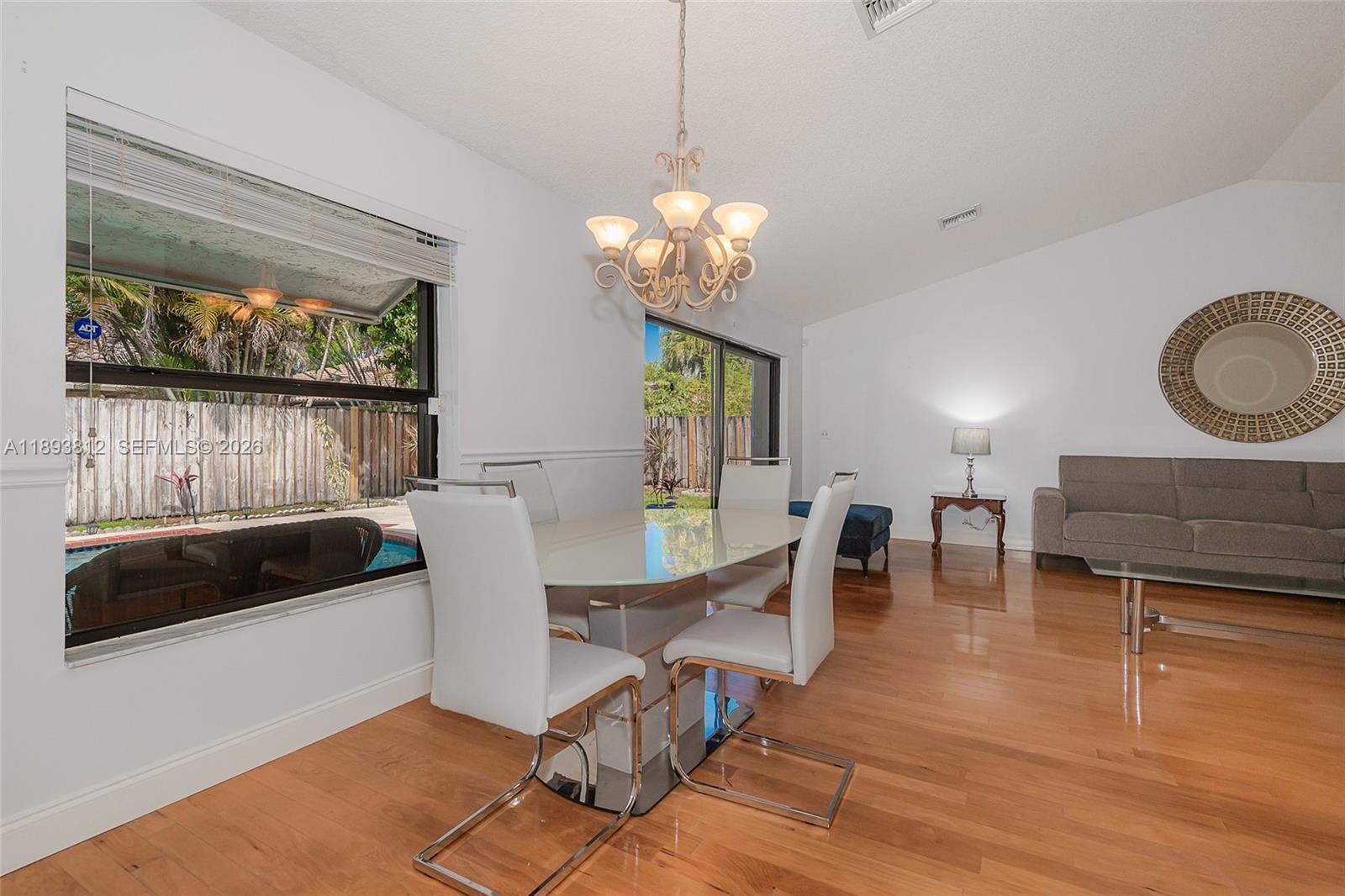 A dining area with a glass table and white chairs sits on hardwood floors — 1855 NW 106th Ter, Plantation FL 33322, PLANTATION, FL