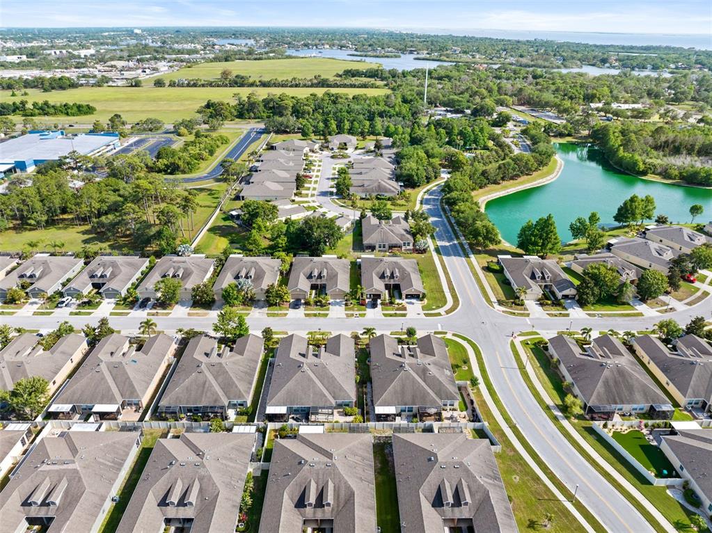 An aerial view shows a suburban neighborhood with rows of houses, streets, and a pond — 2201 PARROT FISH DRIVE, HOLIDAY, FL