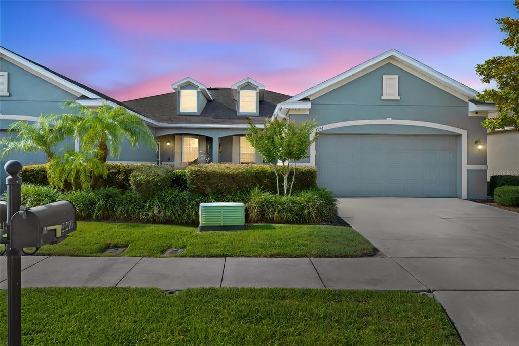 A teal single-story house with a two-car garage and a landscaped front yard at dusk — 2201 PARROT FISH DRIVE, HOLIDAY, FL