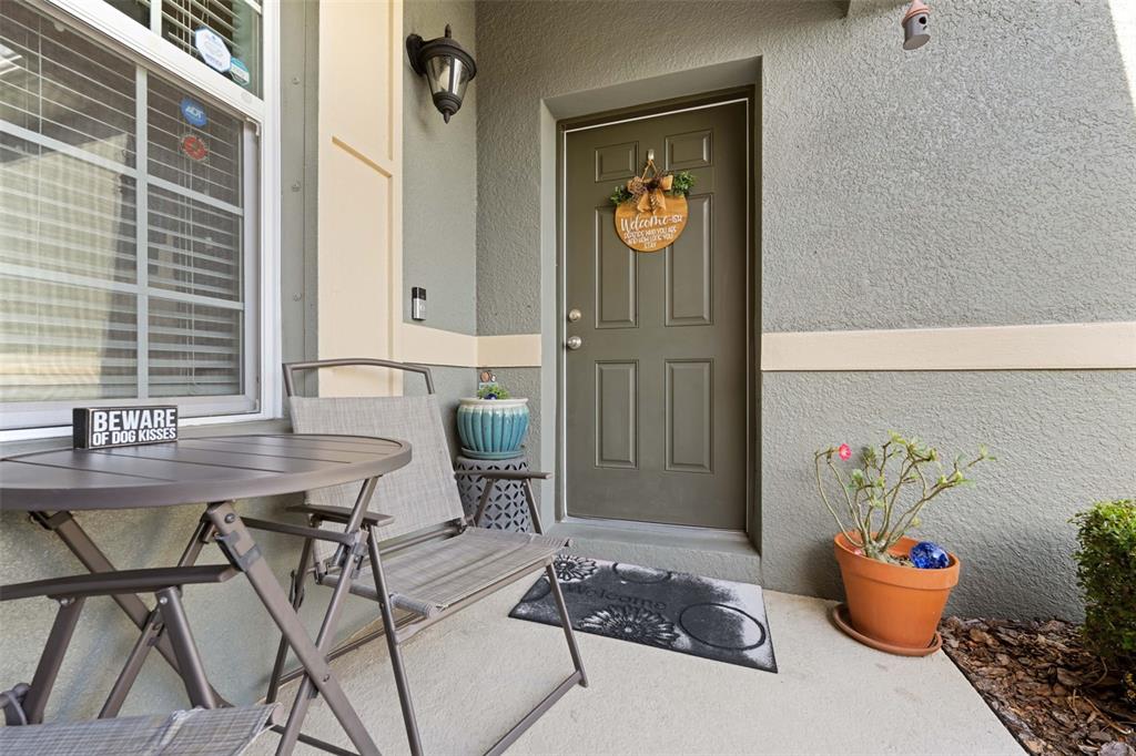 A front porch features a small table, a folding chair, and a potted plant — 2201 PARROT FISH DRIVE, HOLIDAY, FL